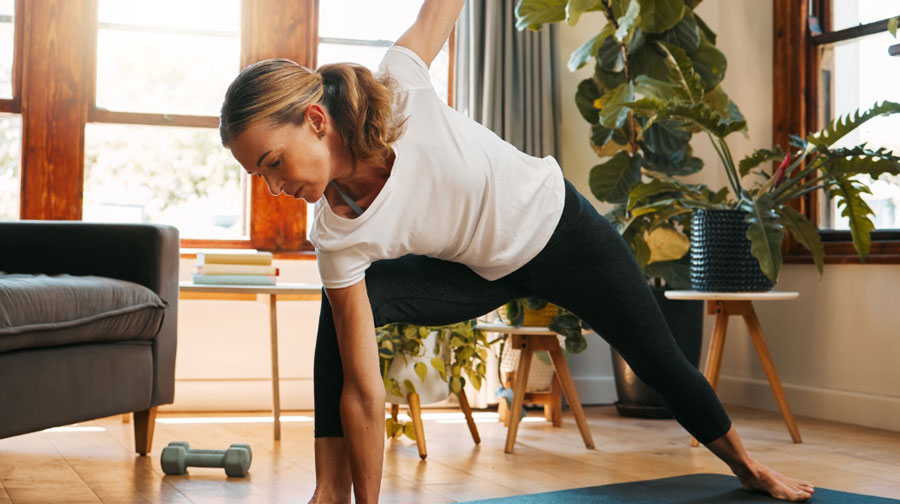 Woman practicing yoga on a mat in her living room