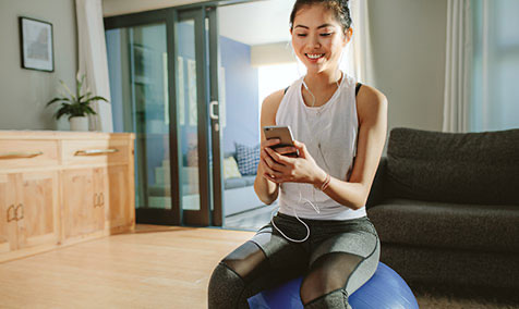 A woman working out at home, looking at her phone