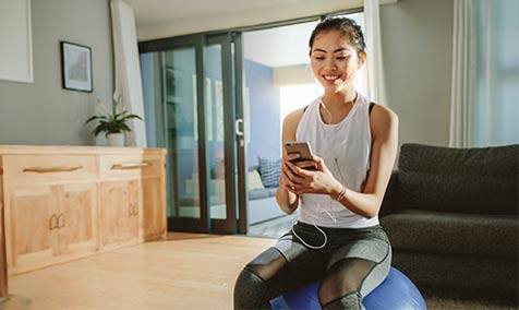 A woman working out at home, looking at her phone