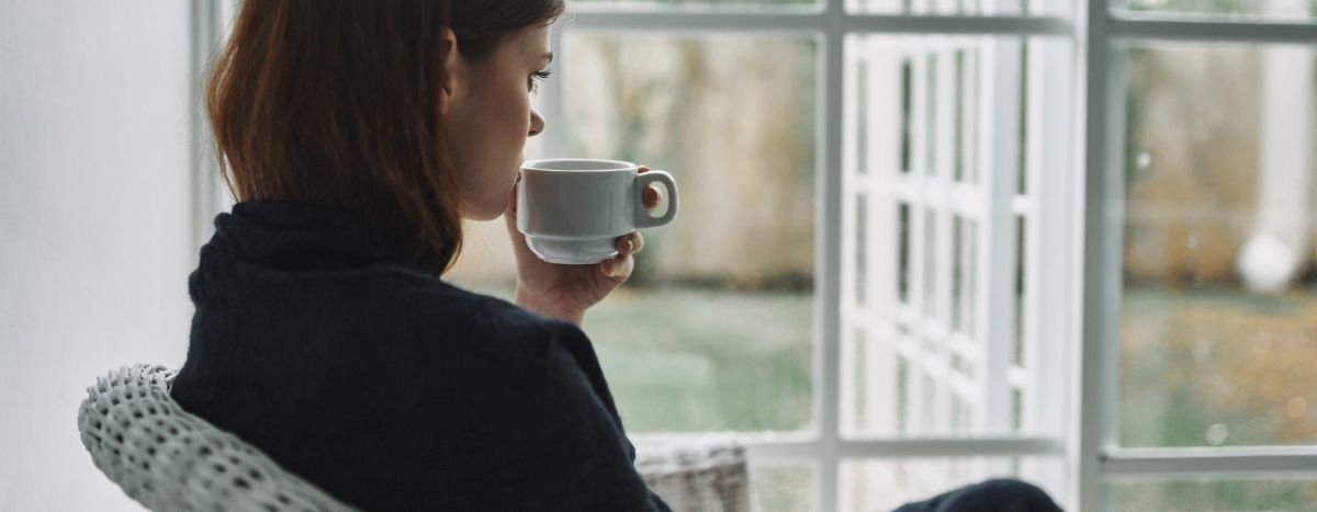A person sips coffee at a window
