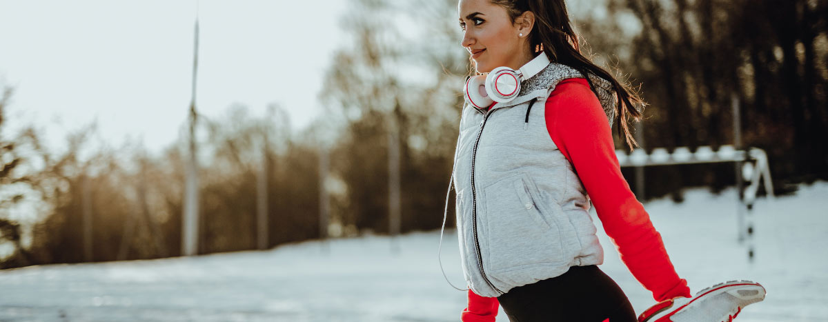 A woman outdoors stretches in active gear