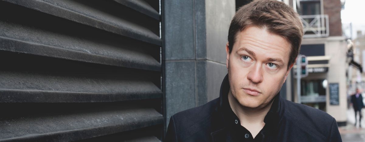 Johann Hari standing in a street looking upward