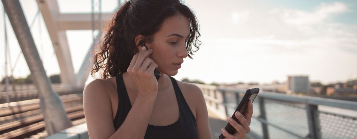 A jogger on a bridge adjusts their music playlist