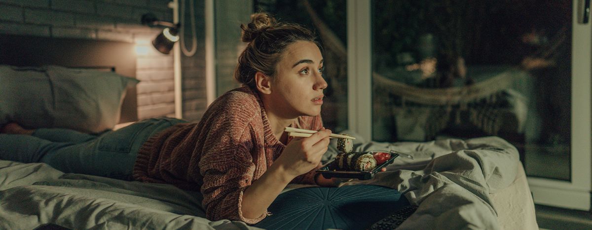 Person eating food in bed | Is it healthy to eat before bed