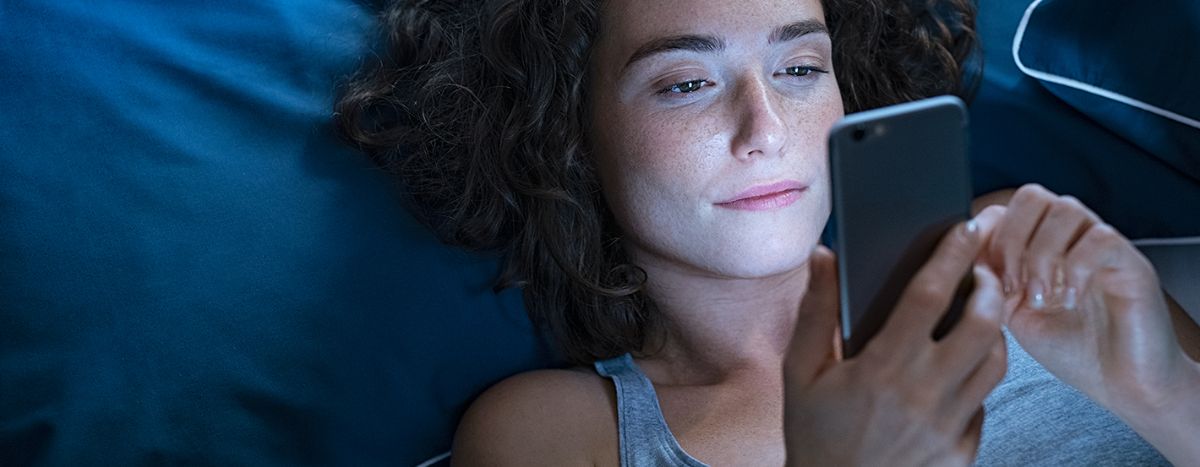 AIA Vitality | Think Well | Can we have healthy relationship with technology? Image of person in bed on their phone