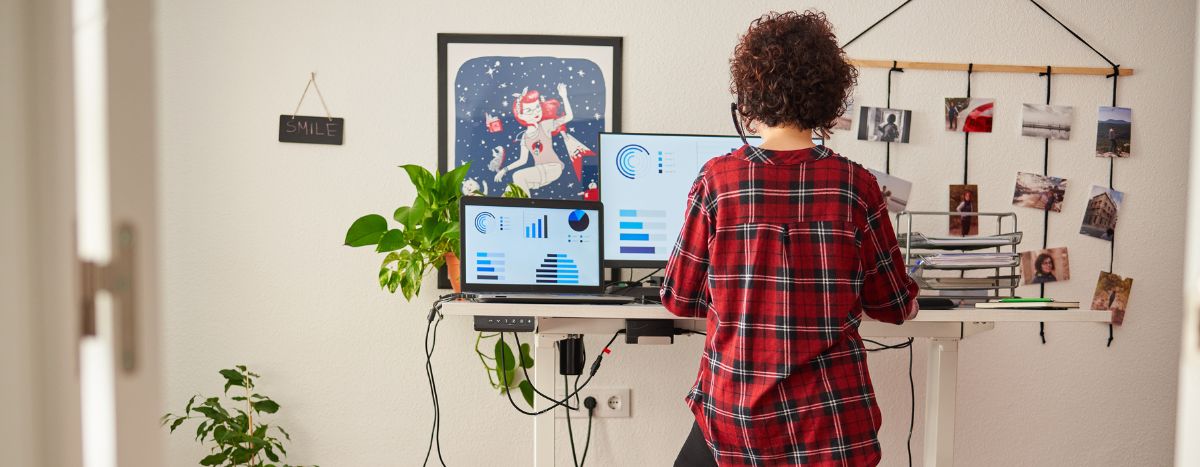 Person using a standing desk looking at computer screens