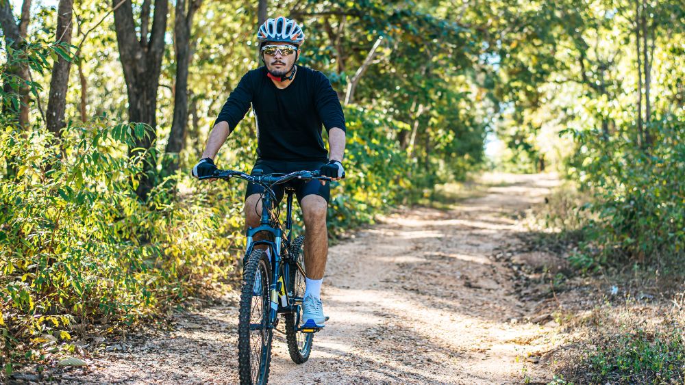 AIA Vitality | Move Well | How to exercise safely during summer | Person riding a mountain bike down a dirt trail