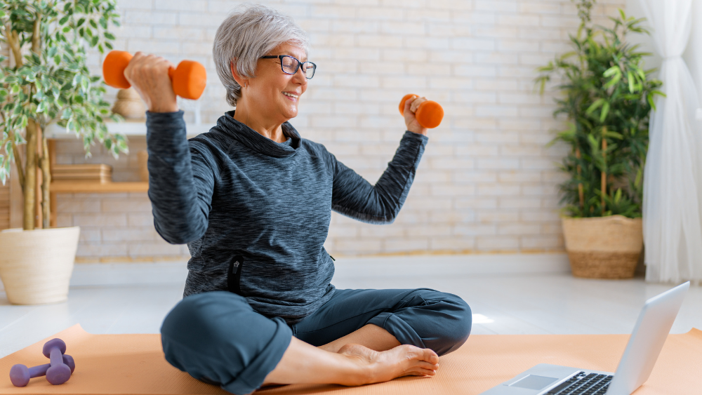 Person lifting weights while seated in front of laptop