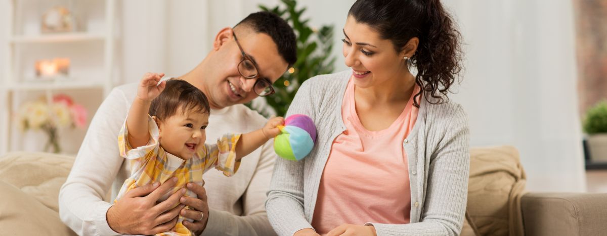 Two parents on couch with toddler playing on one parent's lap