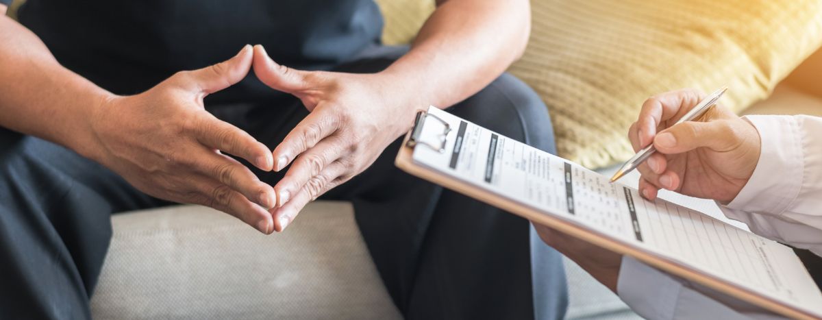 Men's Health Week Header | image of  a person sitting with health professional holding a clipboard
