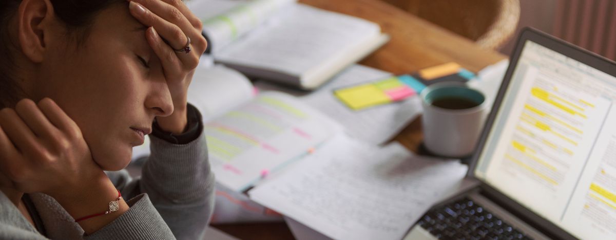 Workplace wellness - image of person with a desk full of paper and laptop