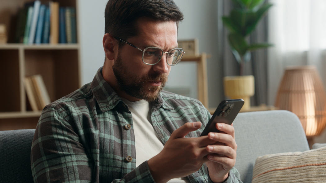 A man looking cautiously at his phone