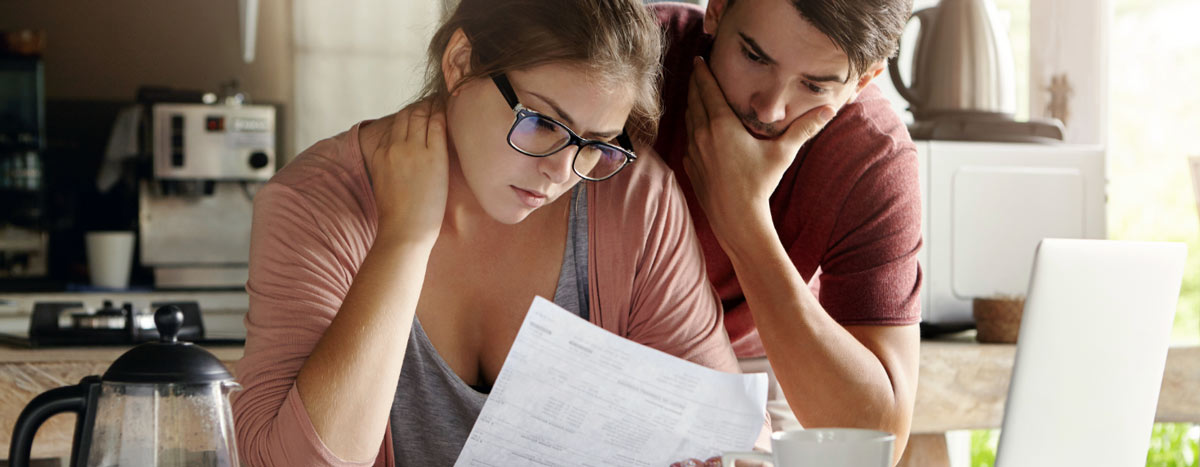 Two people sitting in the kitchen looking at paperwork.
