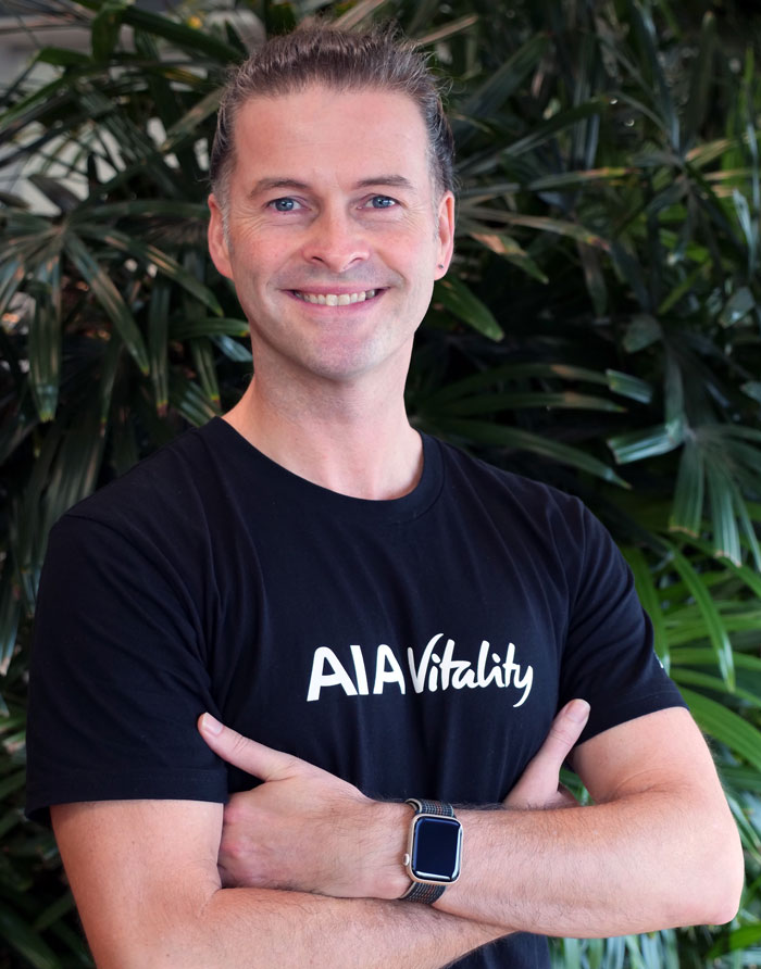 Aaron Gilmore wearing a AIA Vitality branded shirt, smiling.